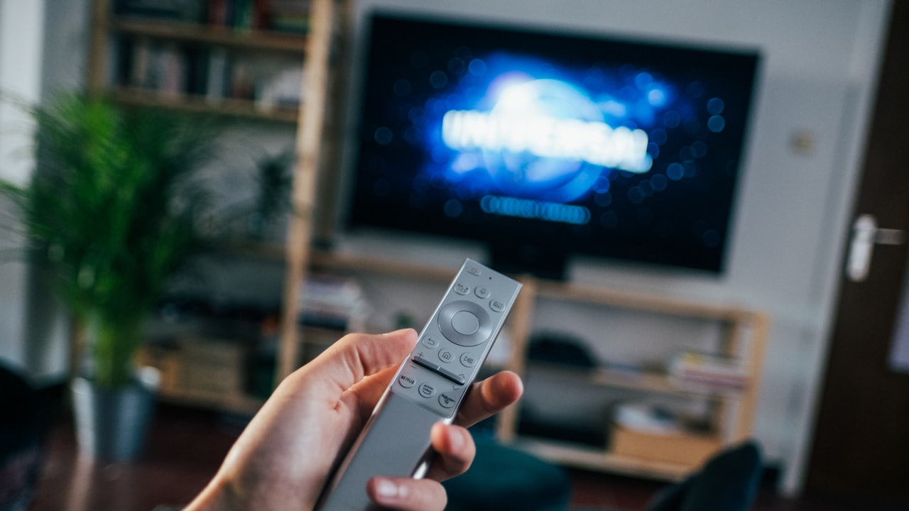 Télécommande de TV connectée pointée vers un téléviseur Android TV allumé
